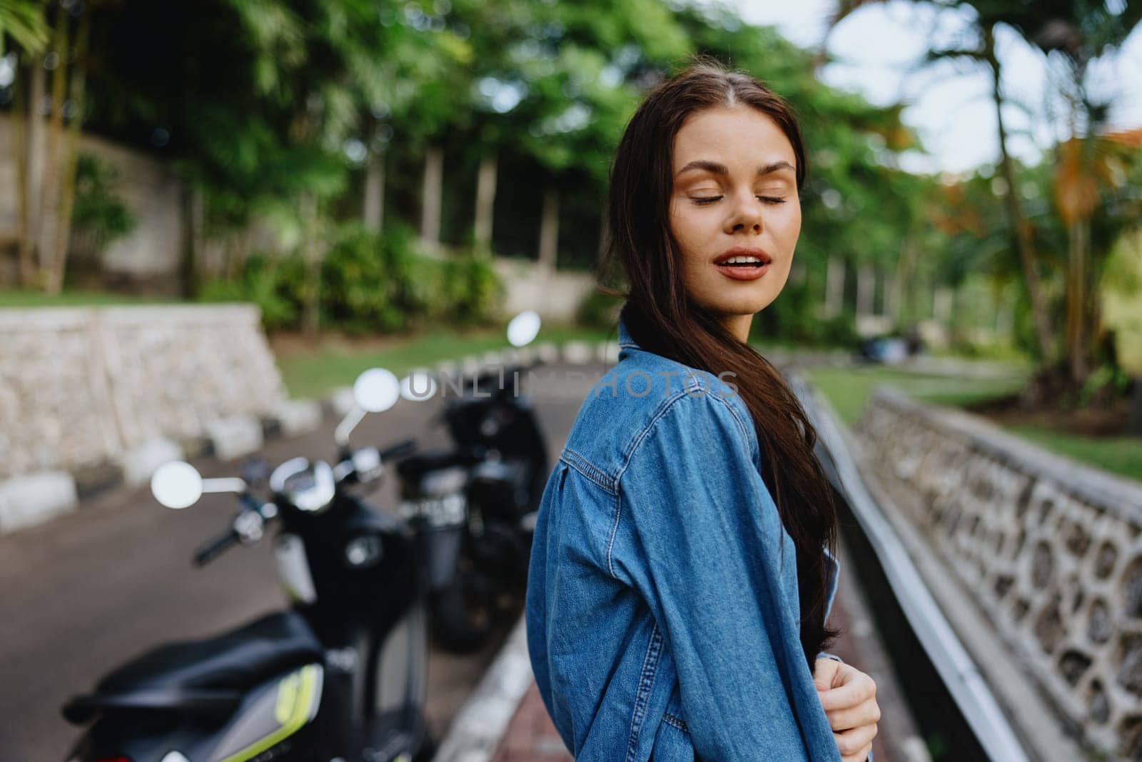 Portrait of a woman brunette smile with teeth walking outside against a backdrop of palm trees in the tropics, summer vacations and outdoor recreation, the carefree lifestyle of a freelance student. by SHOTPRIME