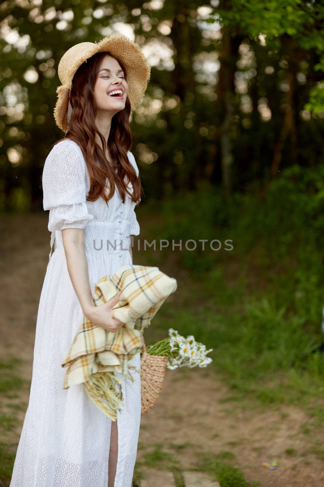 portrait of a happy woman in a light dress and a wicker hat with a plaid in her hands. High quality photo