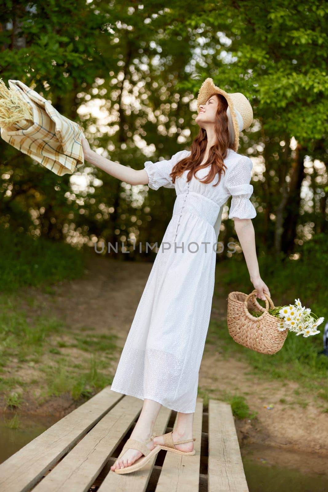 a woman in a light dress, with a plaid and a wicker basket in her hands, is spinning on the pier. High quality photo