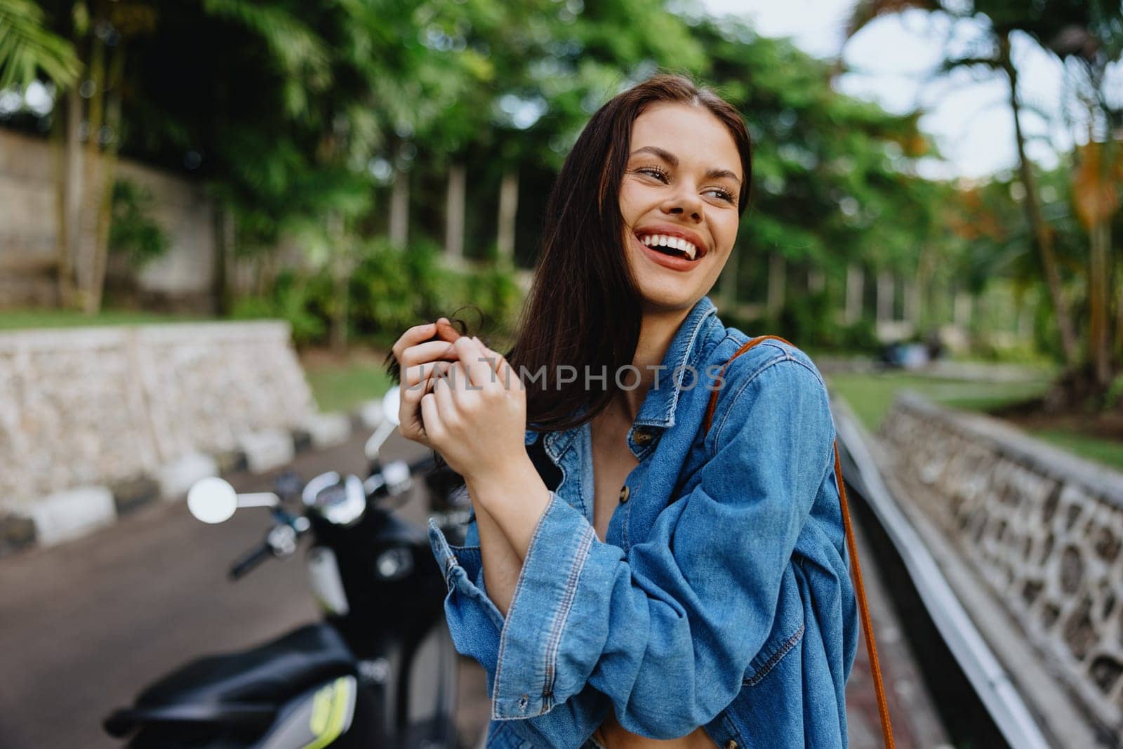 Portrait of a woman brunette smile with teeth walking outside against a backdrop of palm trees in the tropics, summer vacations and outdoor recreation, the carefree lifestyle of a freelance student. by SHOTPRIME