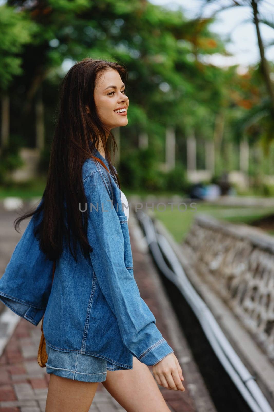 Portrait of a woman brunette smile with teeth walking outside against a backdrop of palm trees in the tropics, summer vacations and outdoor recreation, the carefree lifestyle of a freelance student. High quality photo