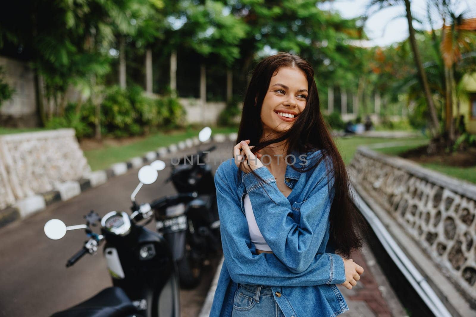 Portrait of a woman brunette smile with teeth walking outside against a backdrop of palm trees in the tropics, summer vacations and outdoor recreation, the carefree lifestyle of a freelance student. High quality photo