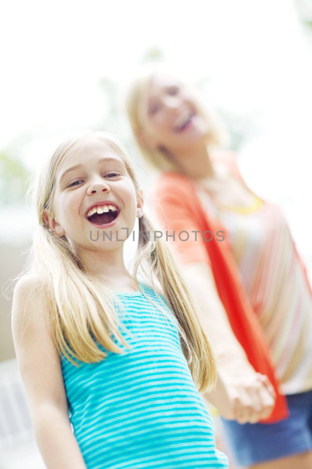 Enjoying a joke with mom. Happy little girl standing outdoors and smiling with her mother