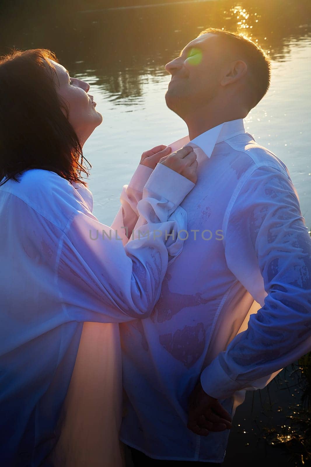 Happy Couple relaxin, having fun and hug on nature near water of river or lake in summer sunny evening during sunset. Family or lovers have date and rest outdoors. Concept of love and friendship