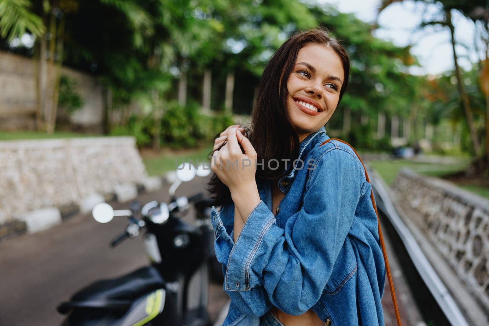 Portrait of a woman brunette smile with teeth walking outside against a backdrop of palm trees in the tropics, summer vacations and outdoor recreation, the carefree lifestyle of a freelance student. High quality photo