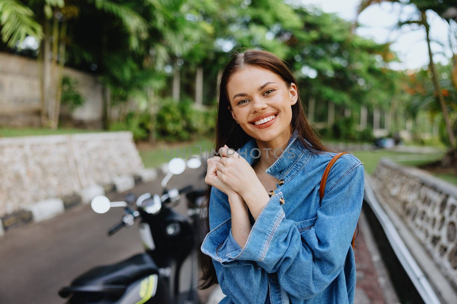 Portrait of a woman brunette smile with teeth walking outside against a backdrop of palm trees in the tropics, summer vacations and outdoor recreation, the carefree lifestyle of a freelance student. by SHOTPRIME