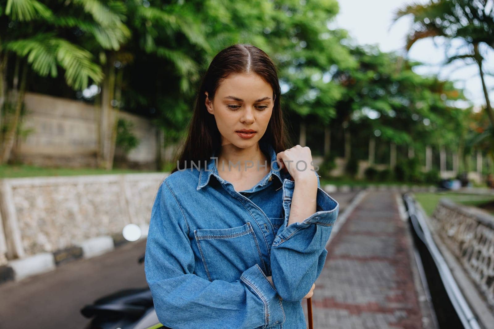 Portrait of a woman brunette smile with teeth walking outside against a backdrop of palm trees in the tropics, summer vacations and outdoor recreation, the carefree lifestyle of a freelance student. by SHOTPRIME