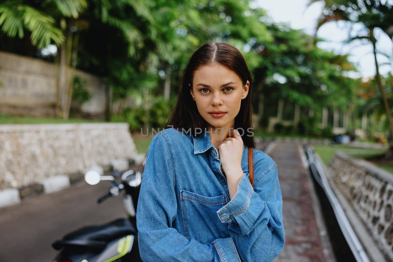 Portrait of a woman brunette smile with teeth walking outside against a backdrop of palm trees in the tropics, summer vacations and outdoor recreation, the carefree lifestyle of a freelance student. by SHOTPRIME