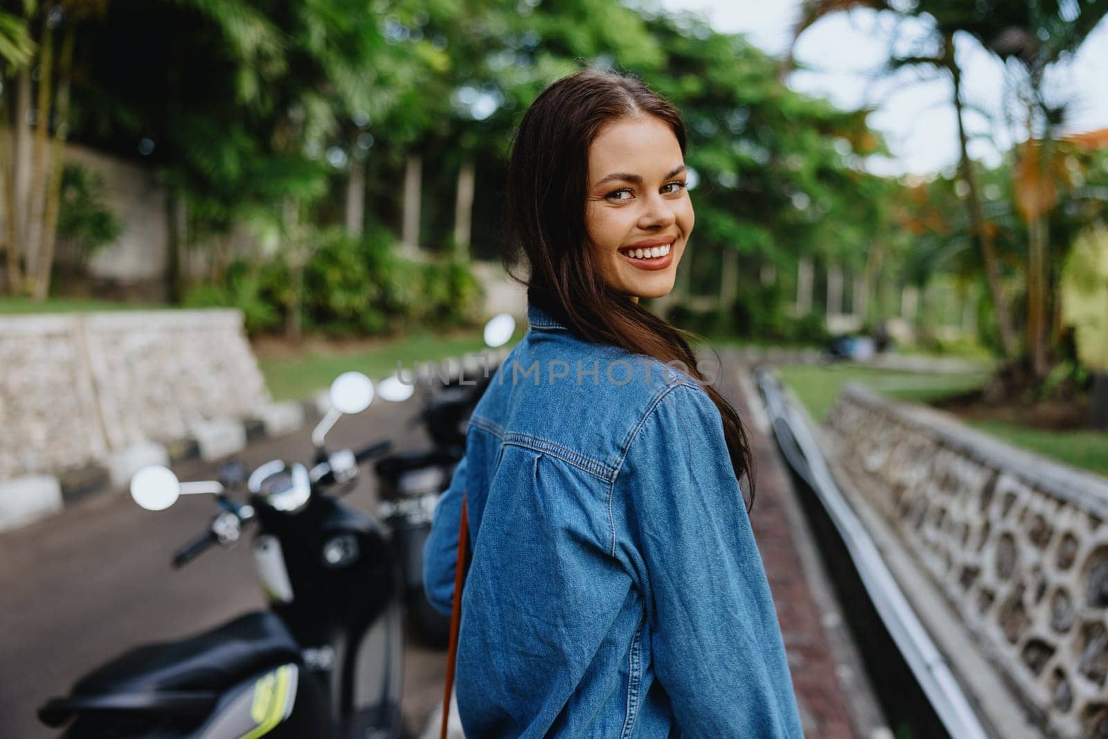 Portrait of a woman brunette smile with teeth walking outside against a backdrop of palm trees in the tropics, summer vacations and outdoor recreation, the carefree lifestyle of a freelance student. High quality photo