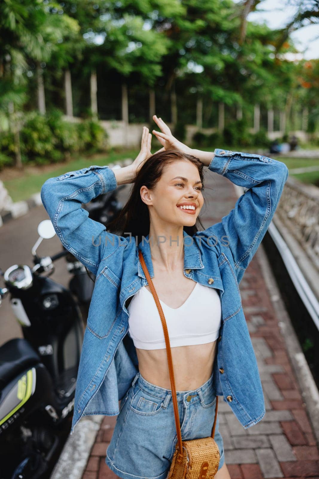 Portrait of a woman brunette smile with teeth walking outside against a backdrop of palm trees in the tropics, summer vacations and outdoor recreation, the carefree lifestyle of a freelance student. High quality photo