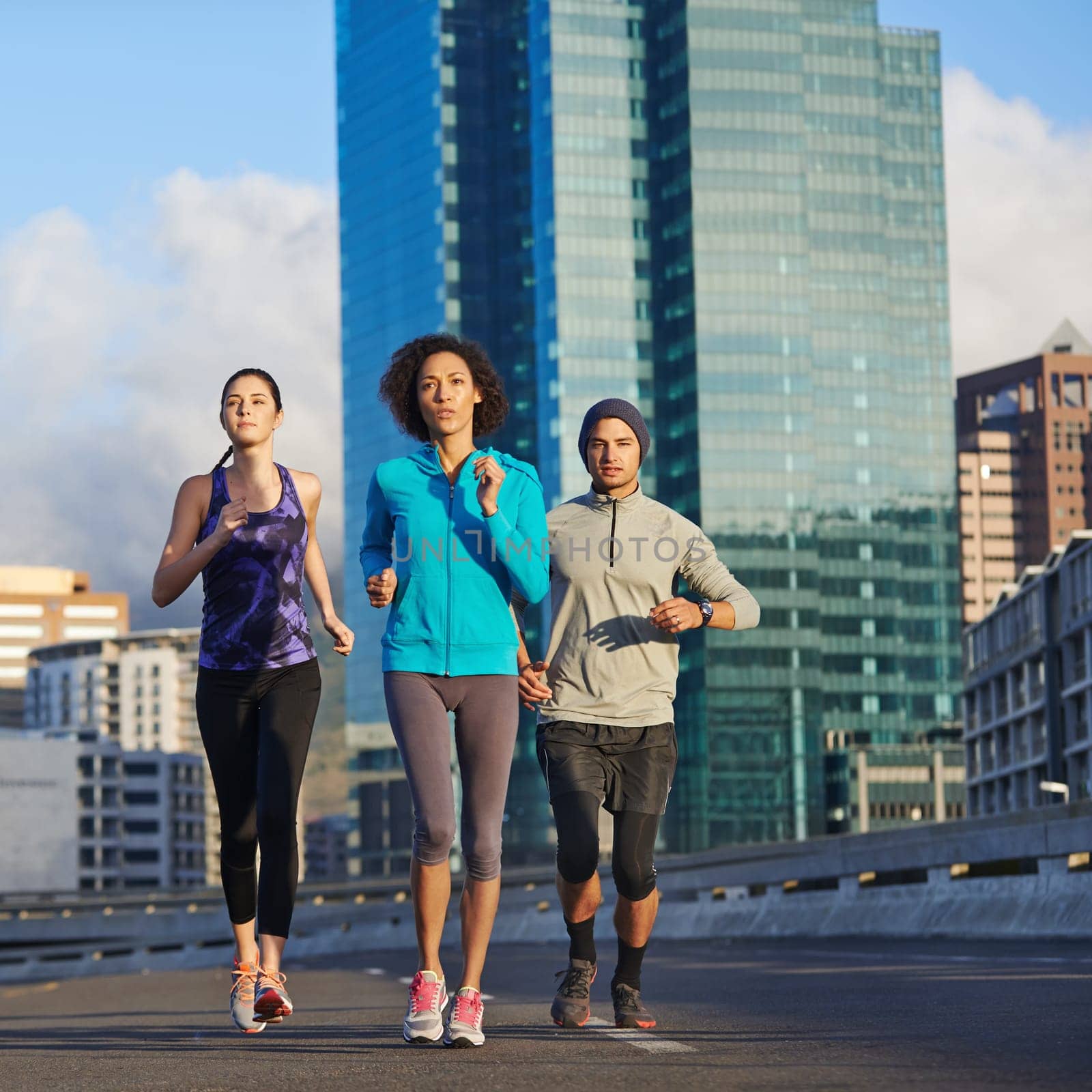 Running down the mileage. three young joggers out for a run in the city. by YuriArcurs