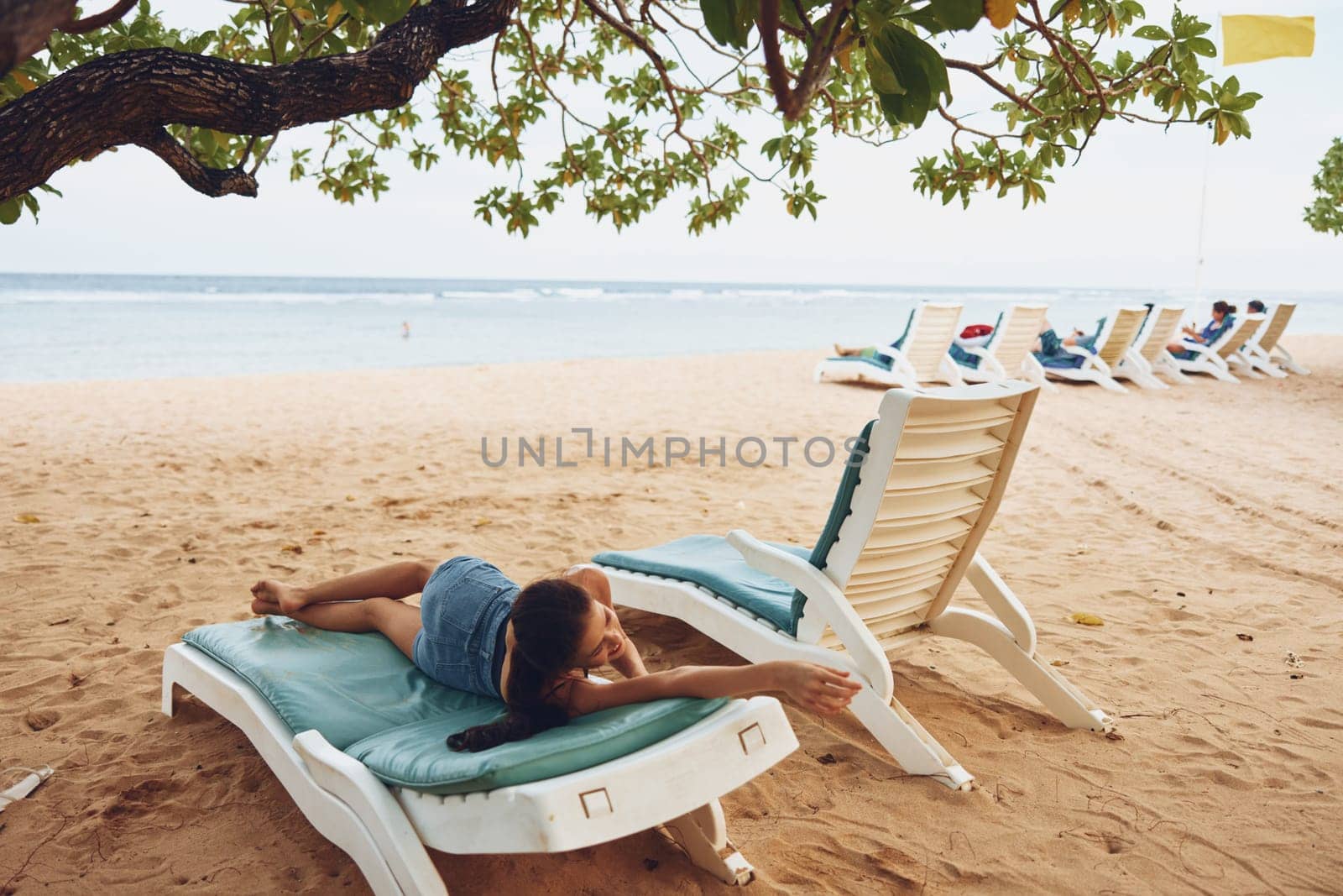 woman sea beach caucasian sand beach summer smiling sunbed sun attractive enjoy beautiful female ocean lifestyle blue chair hat resort chair lying