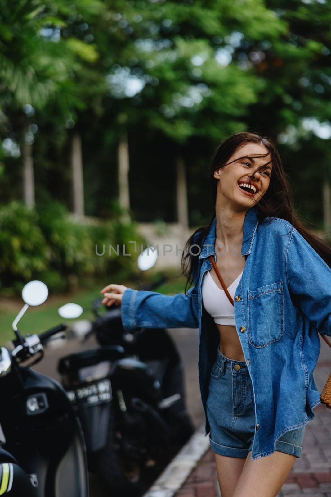 Portrait of a woman brunette smile with teeth running down the street against a backdrop of palm trees in the tropics, summer vacations and outdoor recreation, the carefree lifestyle of a freelance student. High quality photo
