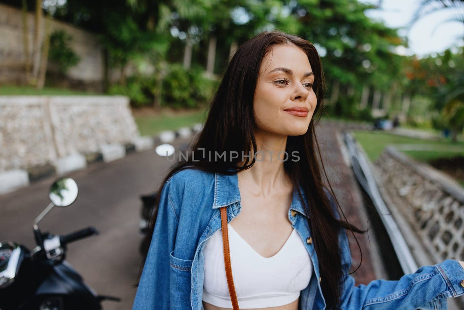 Portrait of a woman brunette smile with teeth walking outside against a backdrop of palm trees in the tropics, summer vacations and outdoor recreation, the carefree lifestyle of a freelance student. by SHOTPRIME