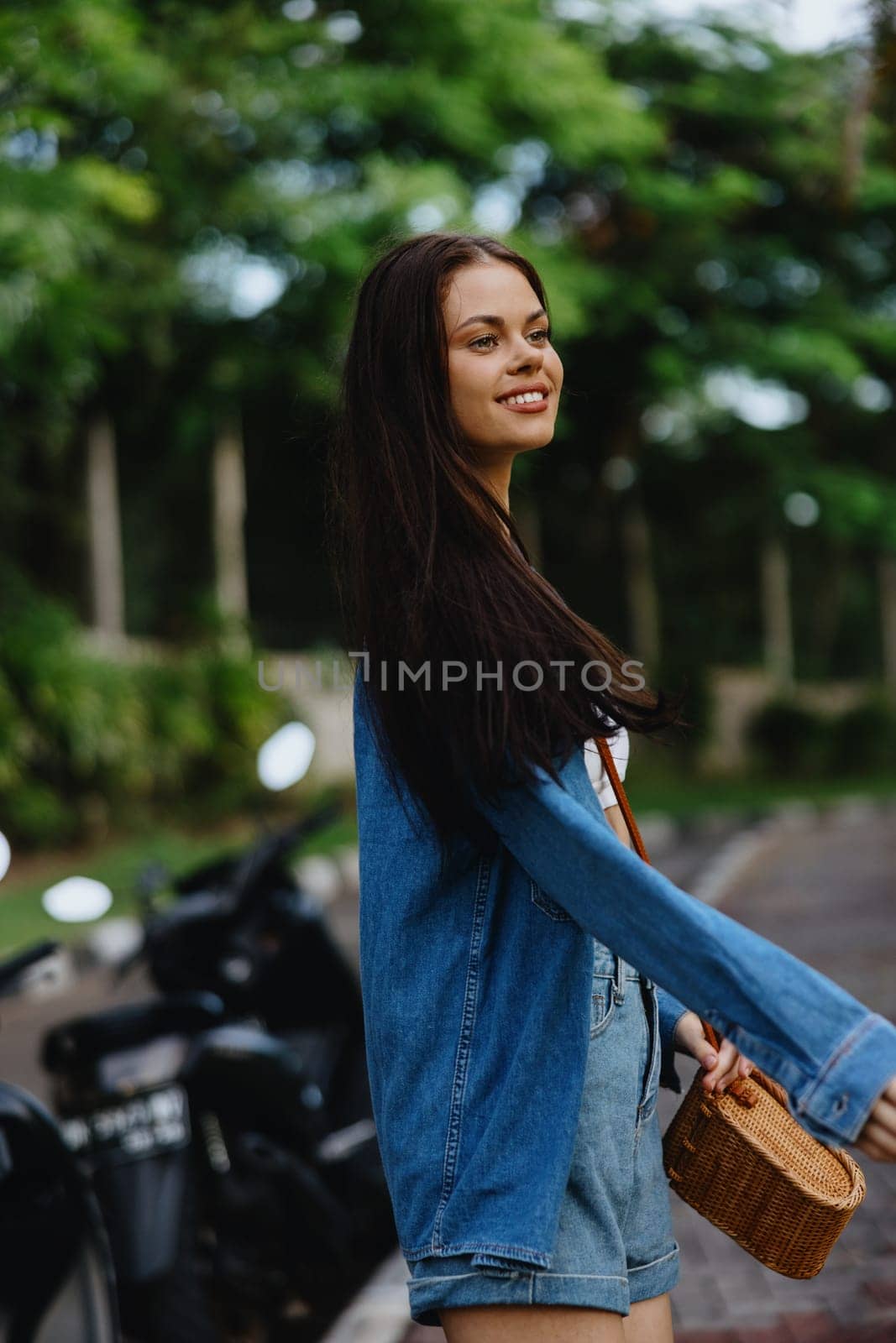 Portrait of a woman brunette smile with teeth running down the street against a backdrop of palm trees in the tropics, summer vacations and outdoor recreation, the carefree lifestyle of a freelance student. High quality photo