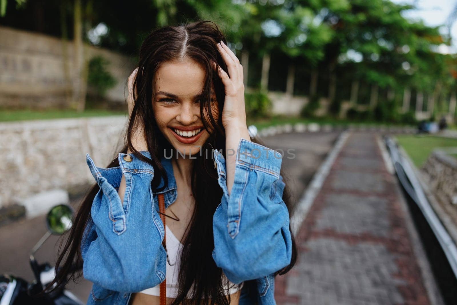 Portrait of a woman brunette smile with teeth walking outside against a backdrop of palm trees in the tropics, summer vacations and outdoor recreation, the carefree lifestyle of a freelance student. by SHOTPRIME