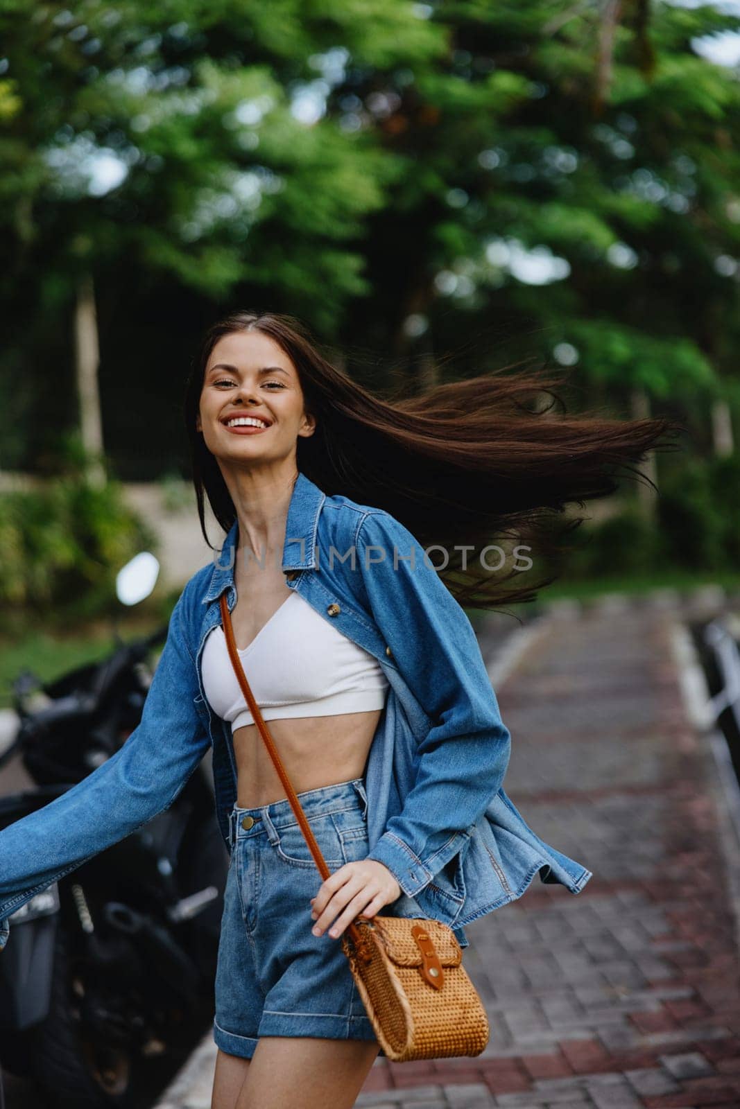 Portrait of a woman brunette smile with teeth running down the street against a backdrop of palm trees in the tropics, summer vacations and outdoor recreation, the carefree lifestyle of a freelance student. High quality photo