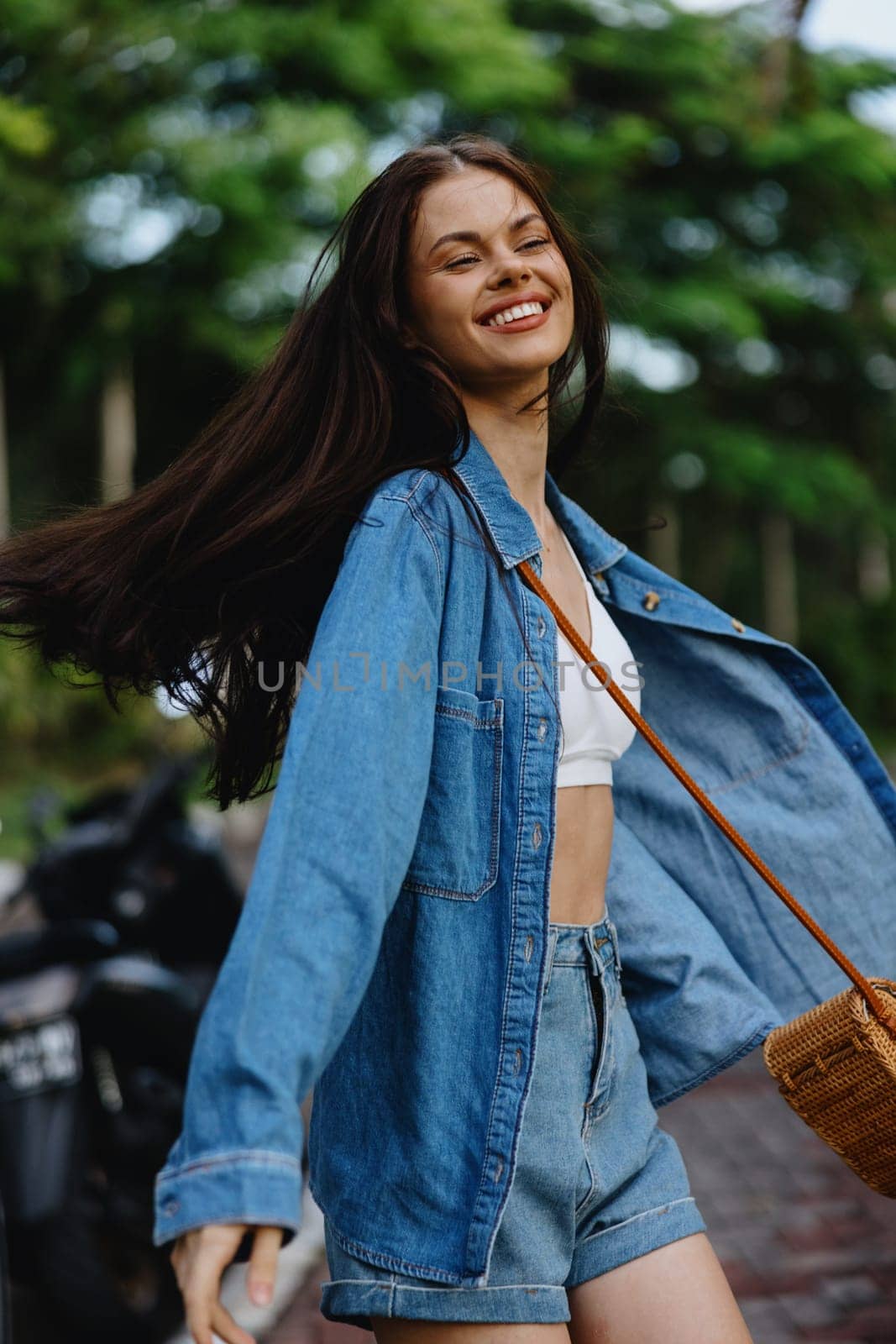 Portrait of woman brunette smile with teeth running down the street against backdrop palm trees in the tropics, summer vacations and outdoor recreation, the carefree lifestyle of a freelance student. by SHOTPRIME