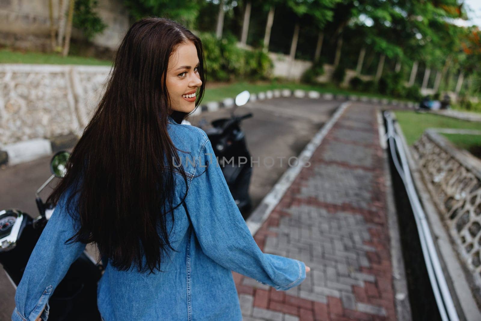 Portrait of a woman brunette smile with teeth walking outside against a backdrop of palm trees in the tropics, summer vacations and outdoor recreation, the carefree lifestyle of a freelance student. High quality photo