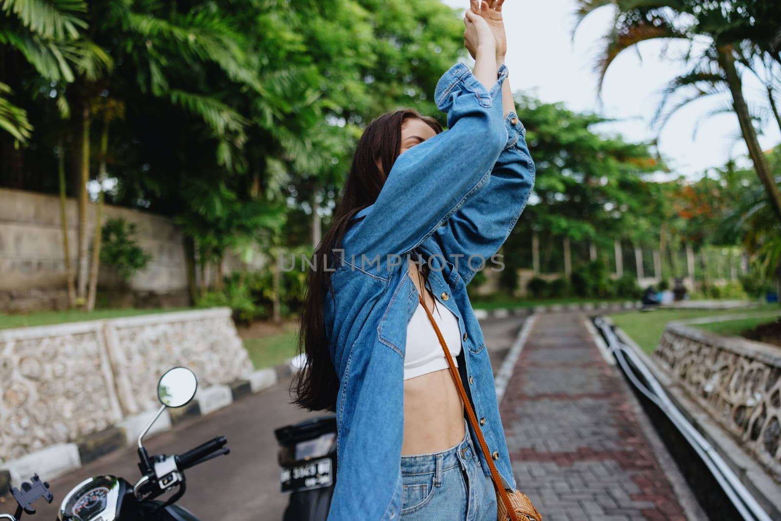 Portrait of a woman brunette smile with teeth walking outside against a backdrop of palm trees in the tropics, summer vacations and outdoor recreation, the carefree lifestyle of a freelance student. High quality photo