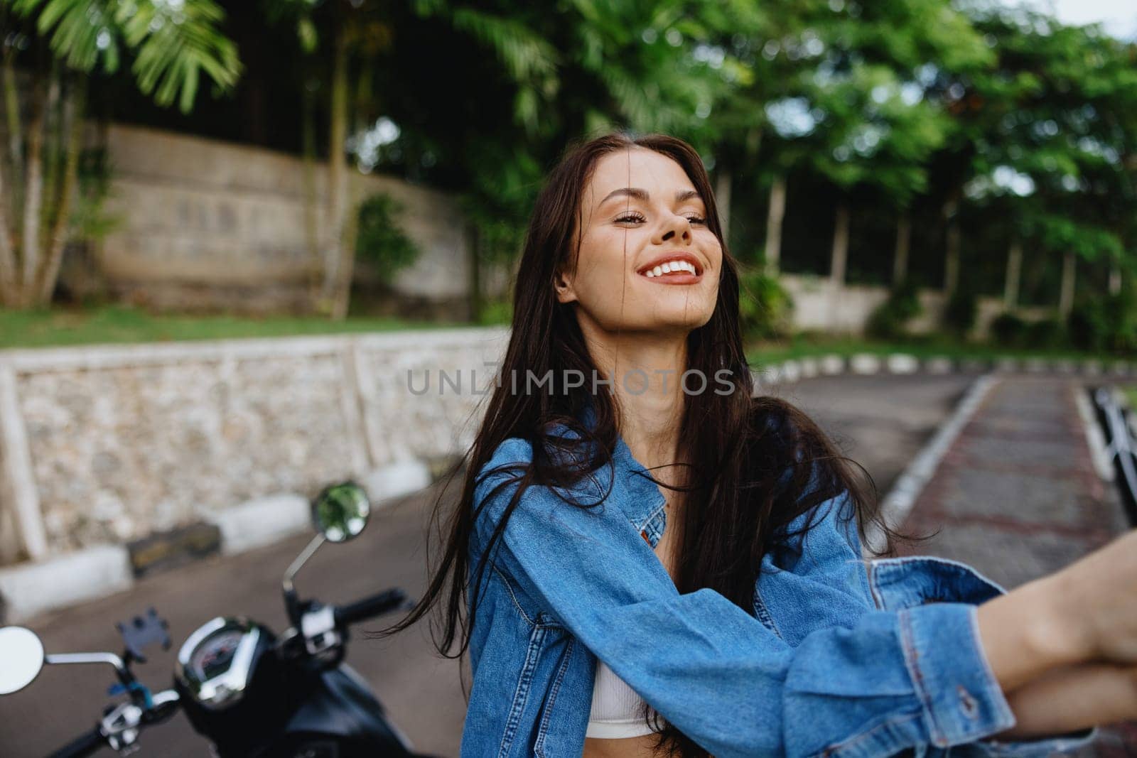 Portrait of a woman brunette smile with teeth walking outside against a backdrop of palm trees in the tropics, summer vacations and outdoor recreation, the carefree lifestyle of a freelance student. High quality photo