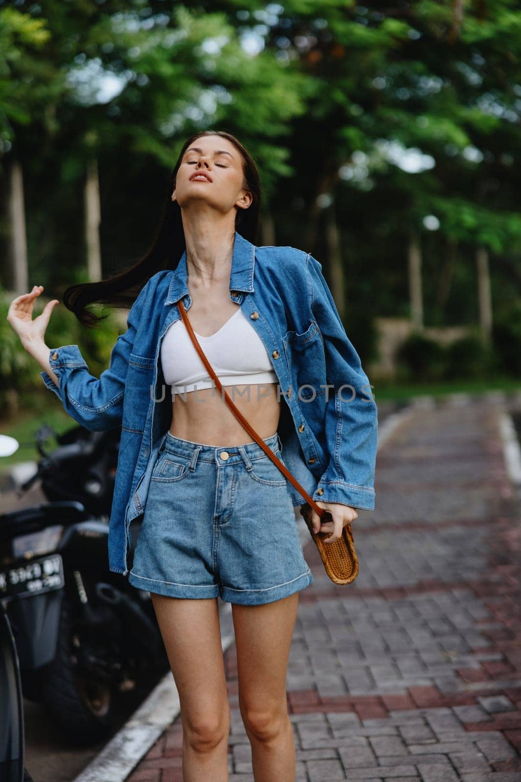 Portrait of woman brunette smile with teeth running down the street against backdrop palm trees in the tropics, summer vacations and outdoor recreation, the carefree lifestyle of a freelance student. by SHOTPRIME