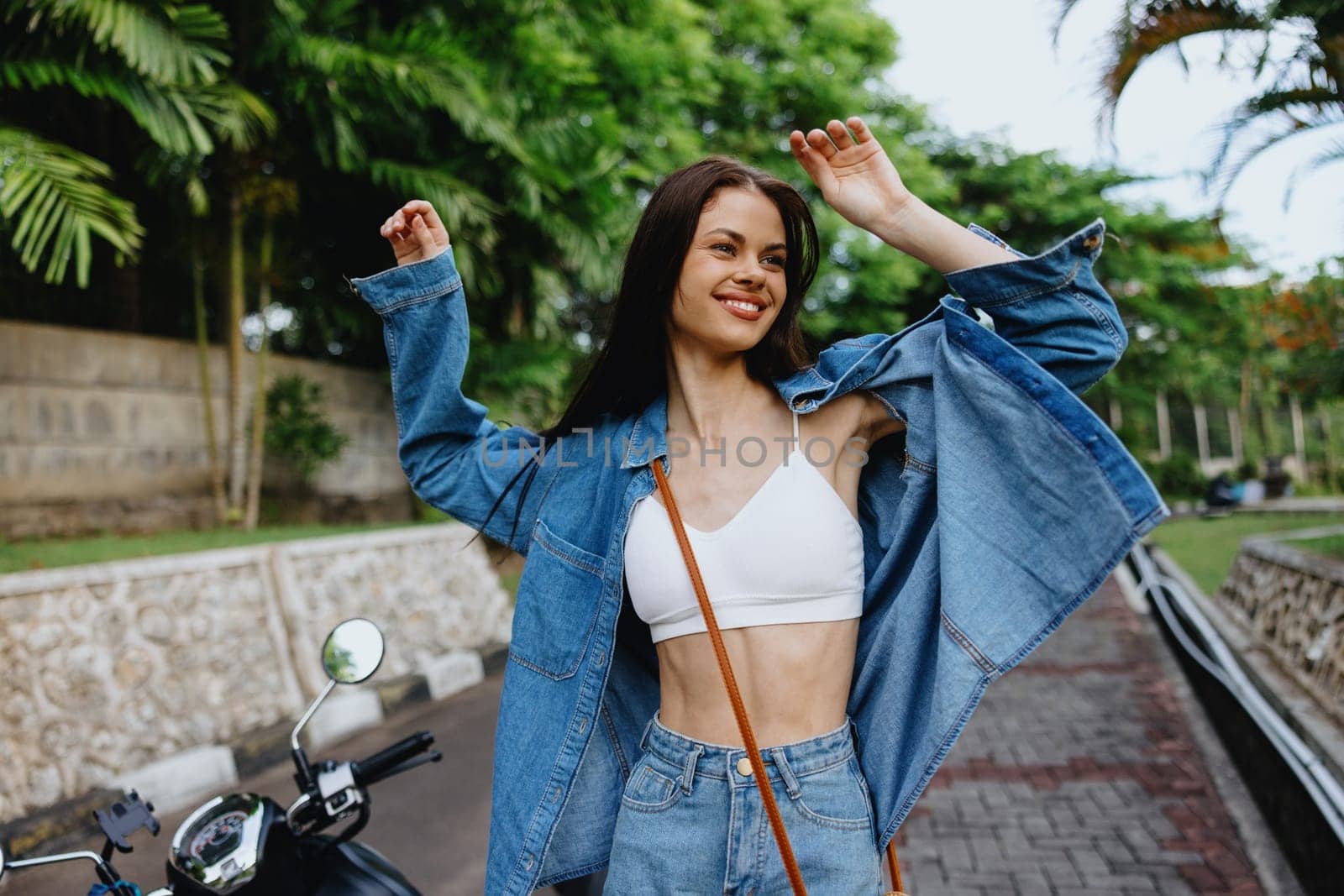 Portrait of a woman brunette smile with teeth walking outside against a backdrop of palm trees in the tropics, summer vacations and outdoor recreation, the carefree lifestyle of a freelance student. by SHOTPRIME