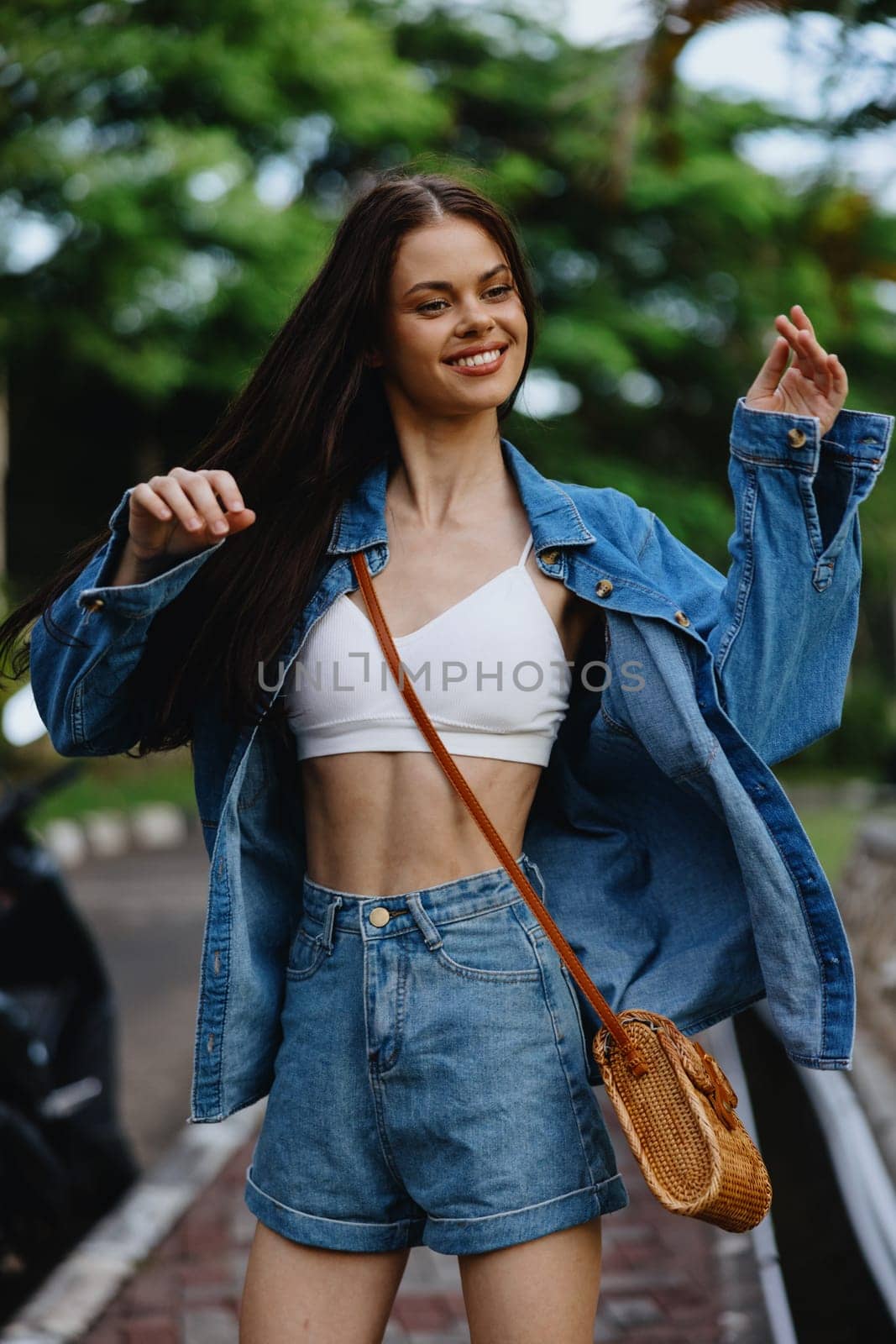 Portrait of woman brunette smile with teeth running down the street against backdrop palm trees in the tropics, summer vacations and outdoor recreation, the carefree lifestyle of a freelance student. by SHOTPRIME