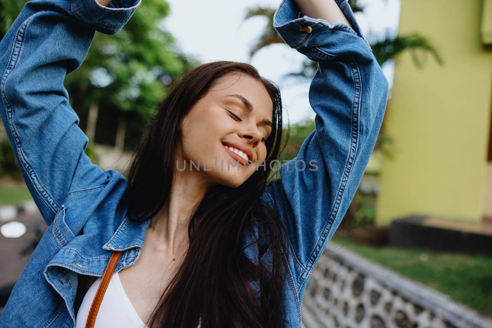 Portrait of a woman brunette smile with teeth walking outside against a backdrop of palm trees in the tropics, summer vacations and outdoor recreation, the carefree lifestyle of a freelance student. by SHOTPRIME