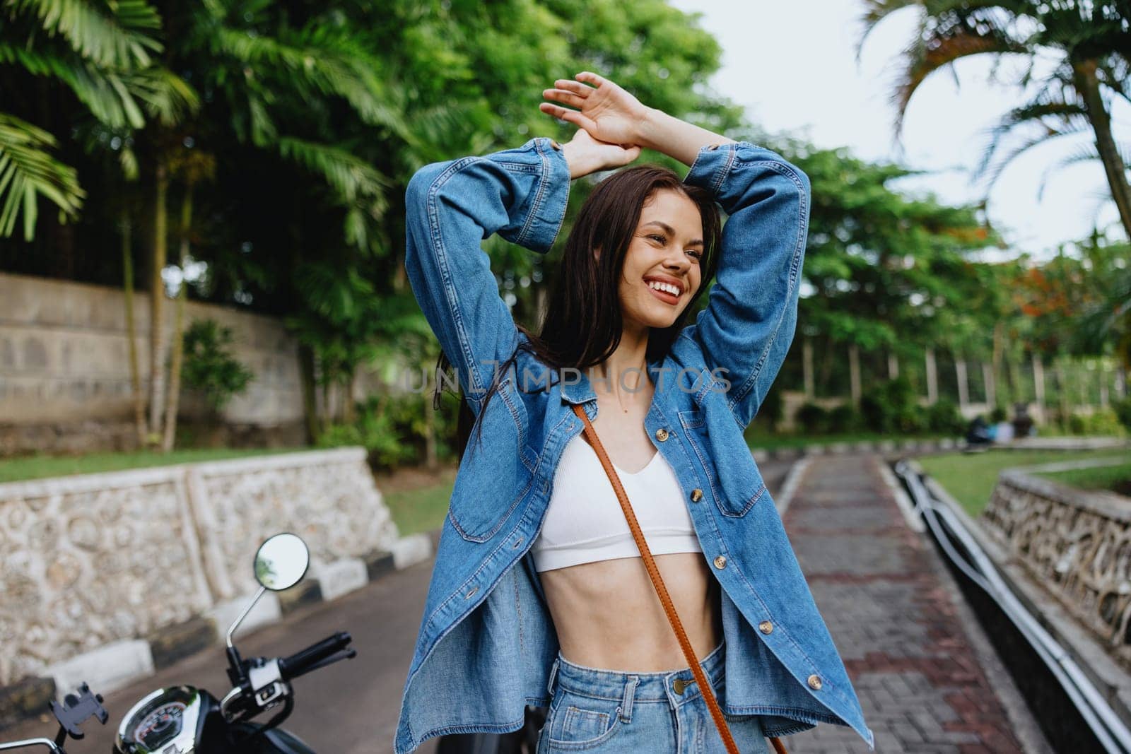 Portrait of a woman brunette smile with teeth walking outside against a backdrop of palm trees in the tropics, summer vacations and outdoor recreation, the carefree lifestyle of a freelance student. High quality photo