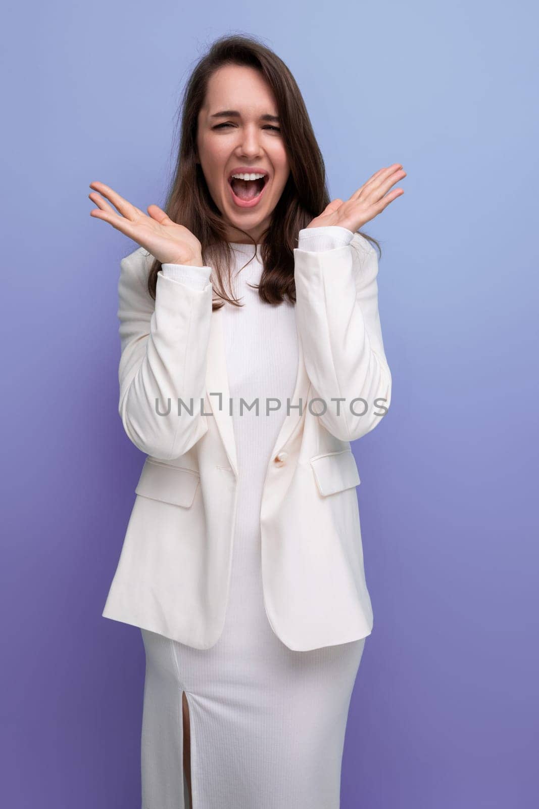 surprised brunette woman young in dress on blue background.