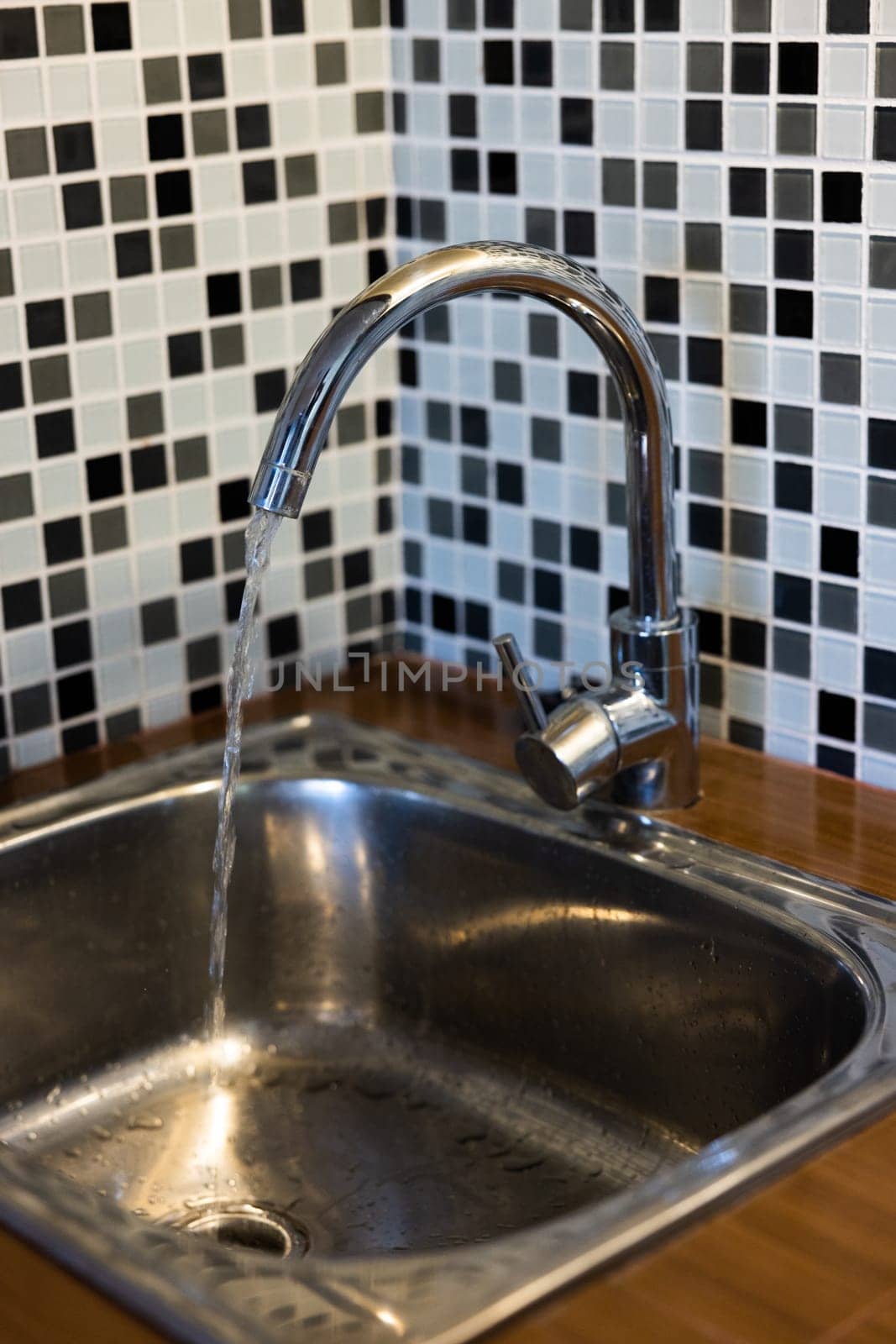 Clean sink with pouring water in the kitchen, metal faucet and sink in an old home interior. by SHOTPRIME