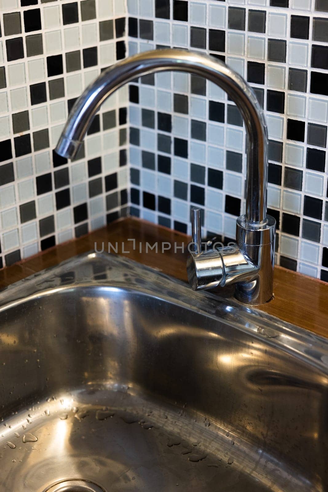 Clean sink with pouring water in the kitchen, metal faucet and sink in an old home interior. by SHOTPRIME