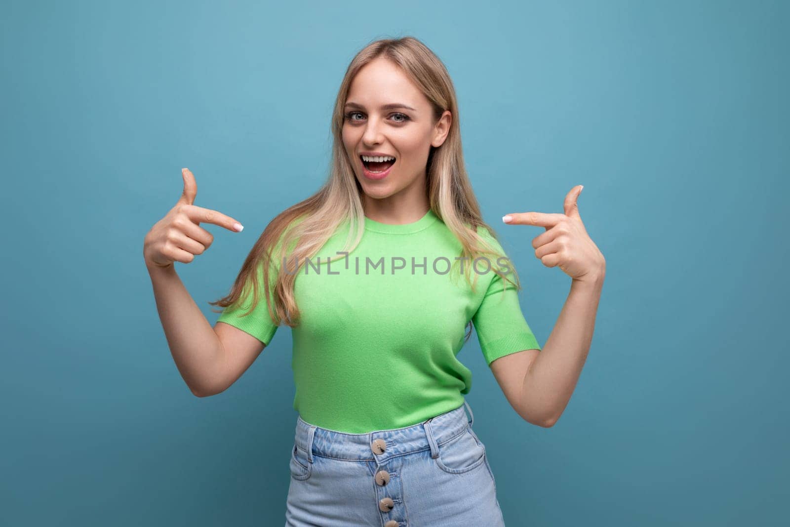 energetic girl in casual outfit demonstrates herself with a finger on a blue background.