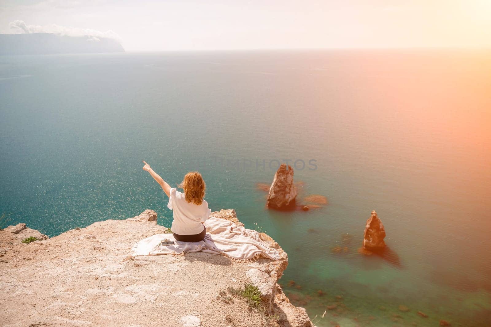 Freelance woman working on a laptop by the sea, typing away on the keyboard while enjoying the beautiful view, highlighting the idea of remote work