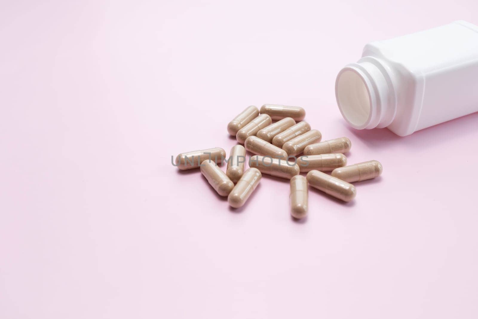 Scattered Softgel Capsules OF Slippery Elm, White Bottle, Container On Pink Background. Dietary Nutritional Supplement, Medication. Ulmus Fulva, Herbal Remedy Concept. Horizontal, Copy space For Text.