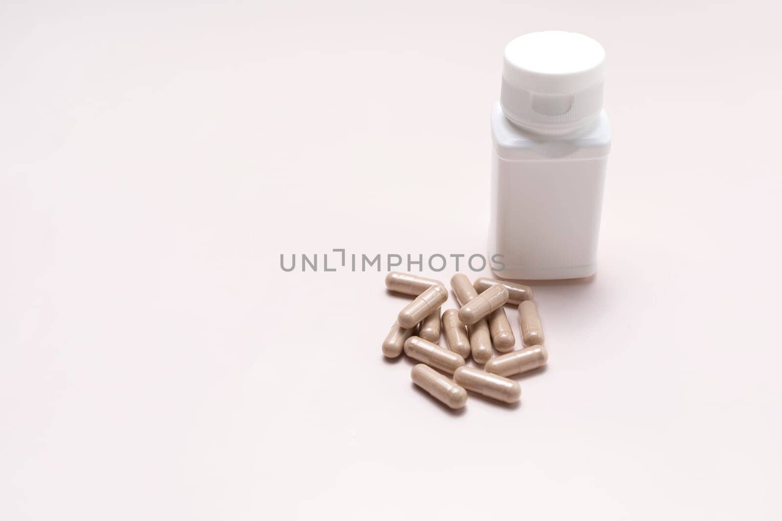 A Handful Of Pills, Capsules Of Slippery Elm And White Bottle On Beige Background, Dietary Nutritional Supplement, Medication. Ulmus Fulva, Herbal Remedy Concept. Horizontal Plane,Copy Space For Text
