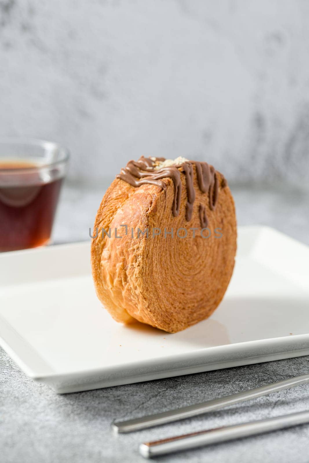 Chocolate New York roll or round croissant with tea on stone table by Sonat