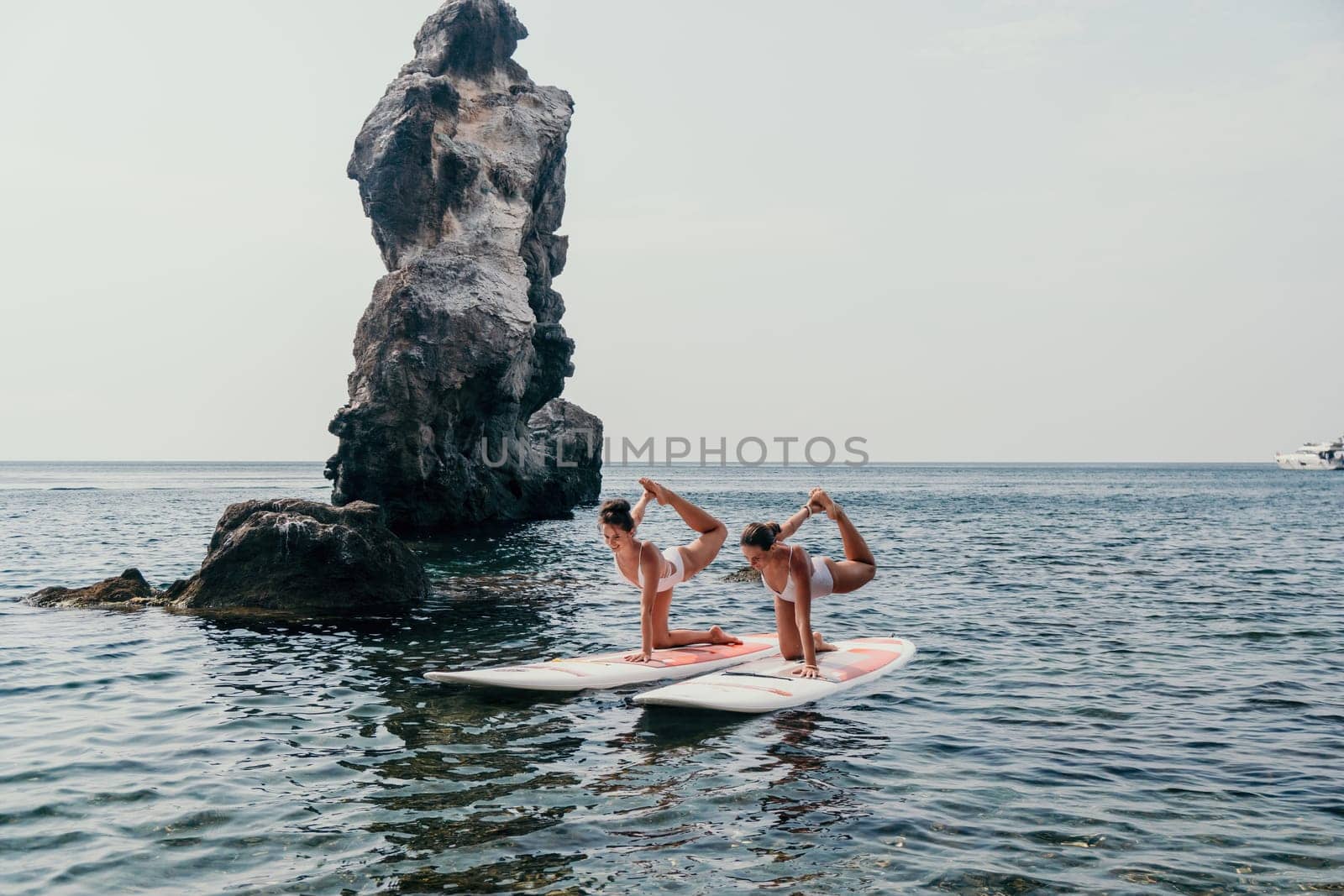 Woman sup yoga. Middle age sporty woman practising yoga pilates on paddle sup surfboard. Female stretching doing workout on sea water. Modern individual hipster outdoor summer sport activity