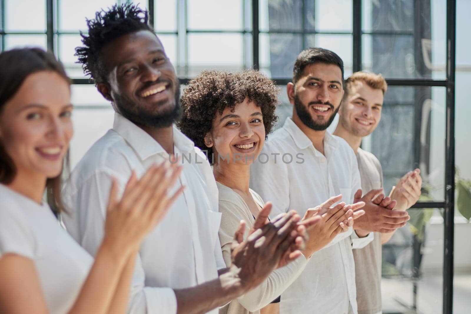 Group of businesspeople sitting in a line and applauding. by Prosto