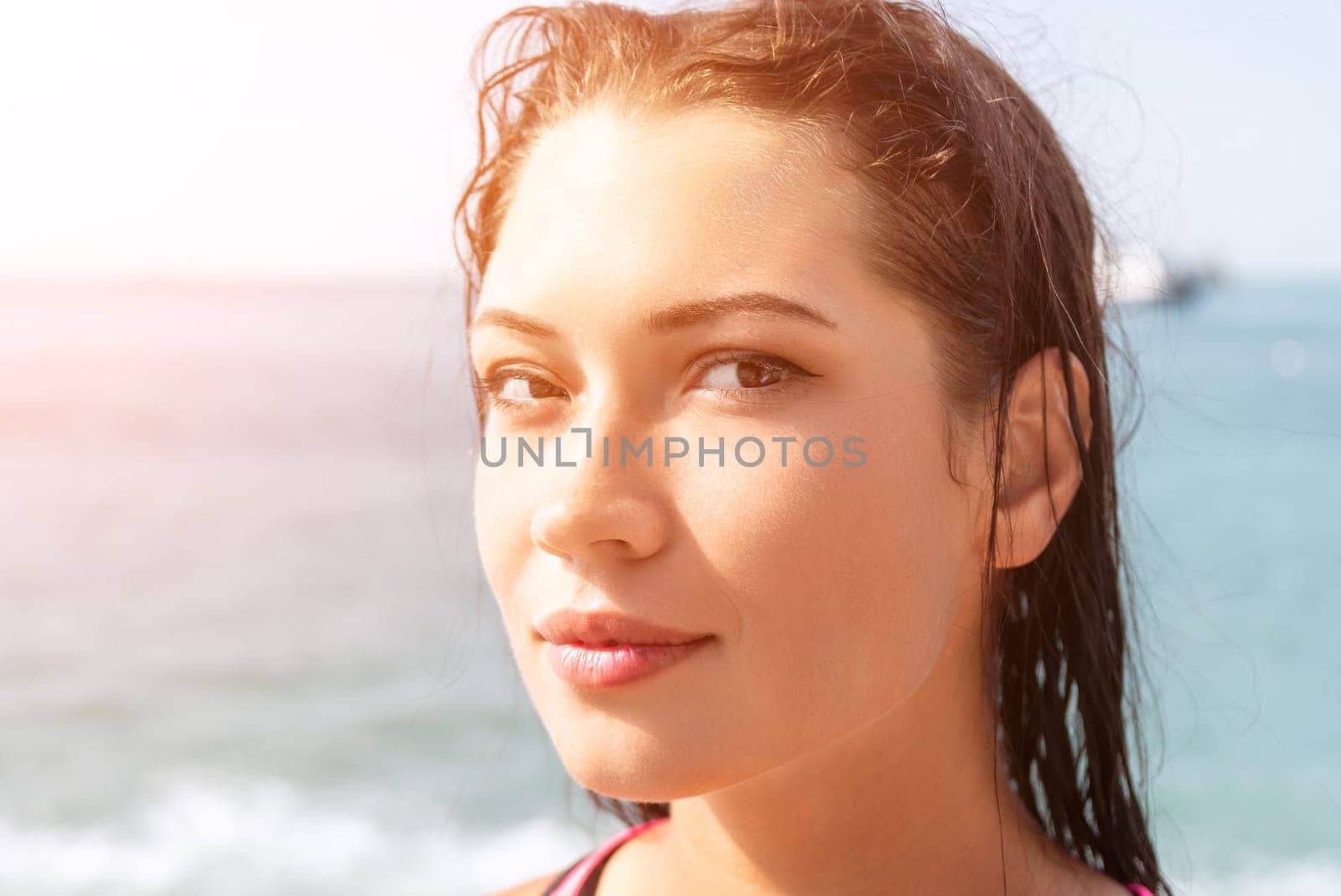Woman sea sup. Close up portrait of beautiful young caucasian woman with black hair and freckles looking at camera and smiling. Cute woman portrait in a pink bikini posing on sup board in the sea