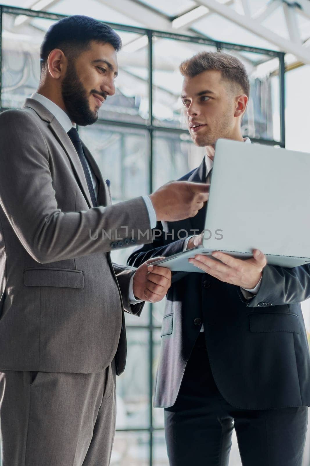 two professional businessmen discussing and using desktop computer in office by Prosto