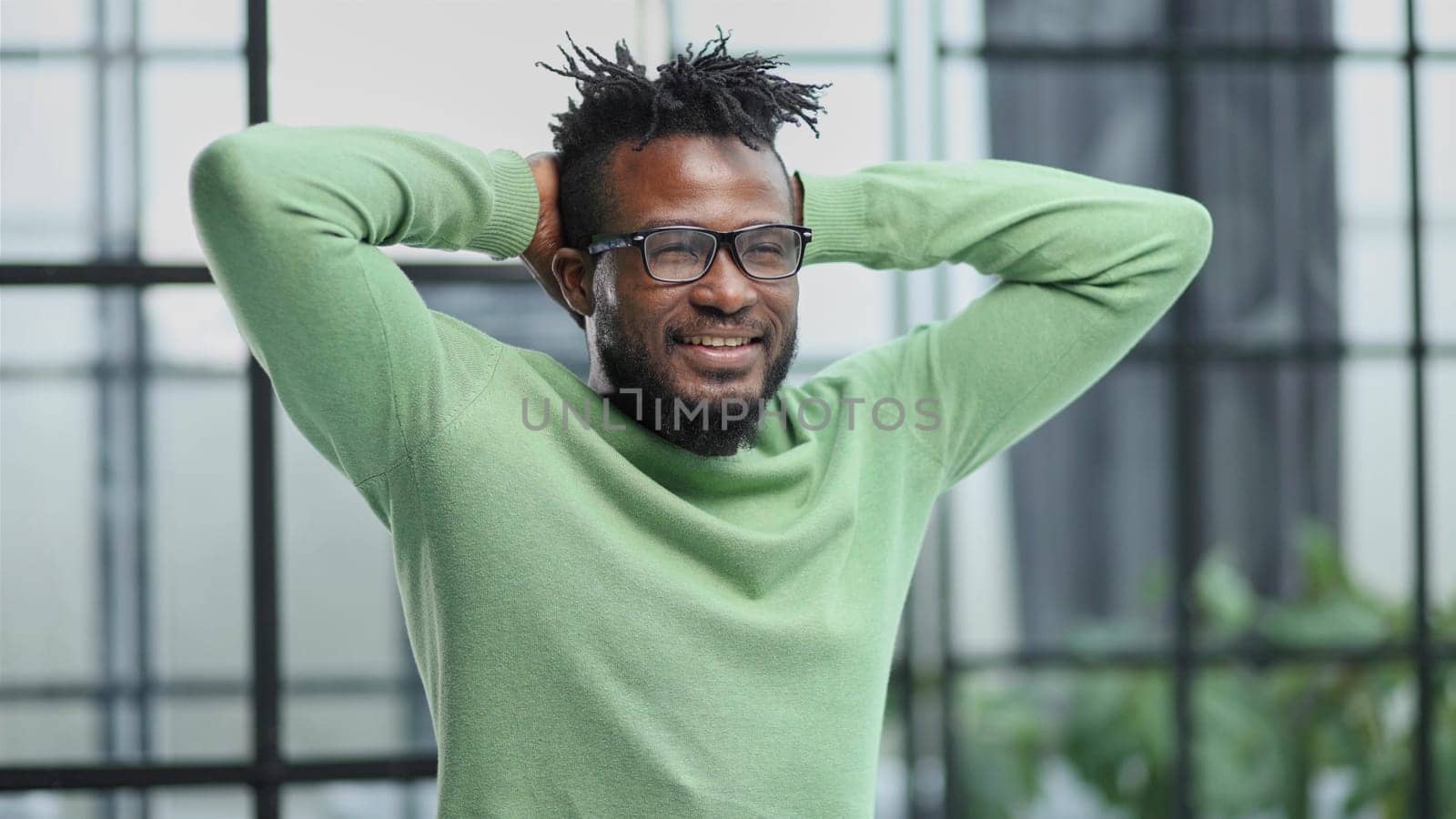 a young man in a green sweatshirt clasped his hands behind his head.