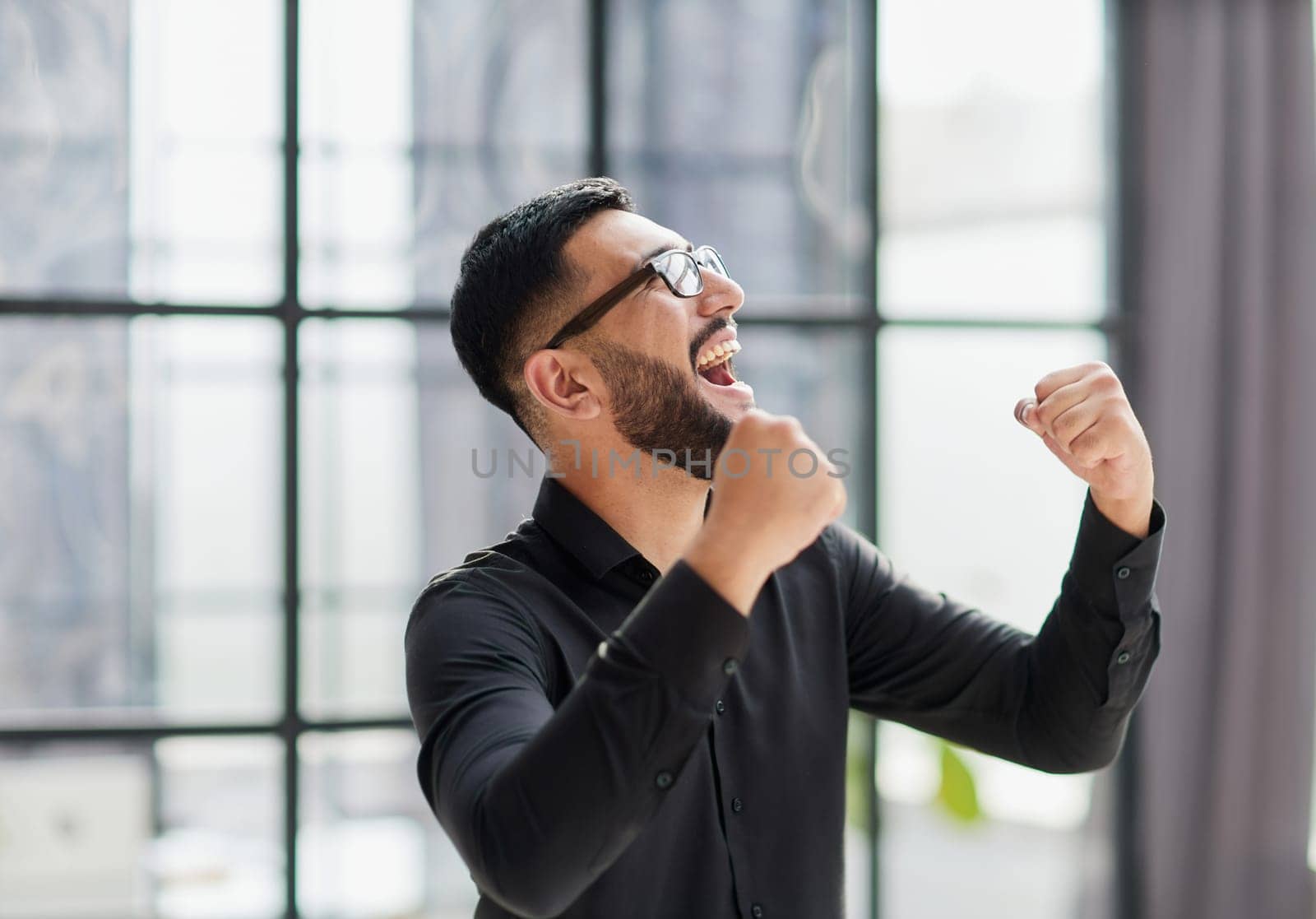 Businessman in stadium crowd, punching air, low angle view