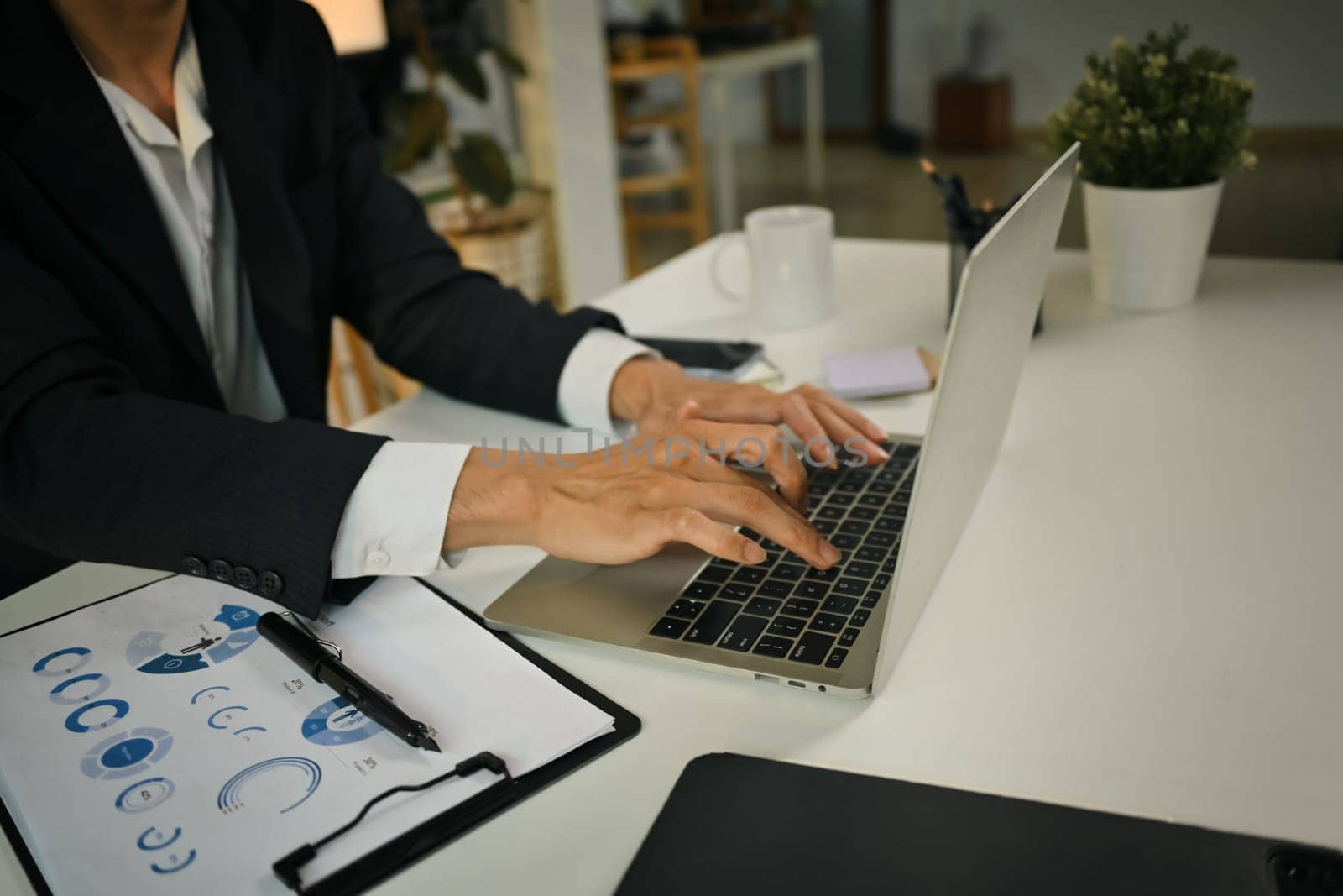 Businessman hands typing on laptop keyboard, checking financial data online or consulting client distantly.