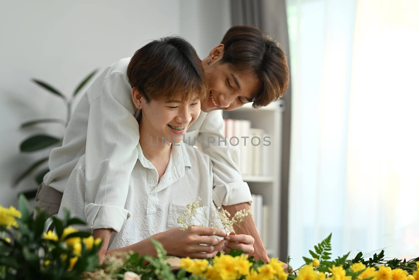 Homosexual, LGBT and relationships. Joyful male gay couple spending time together, enjoying arranging flowers in cozy home.