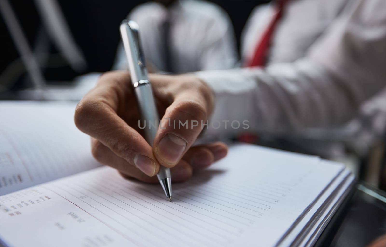 Businessman hand writing note on a notebook close-up. Business man working at office desk.