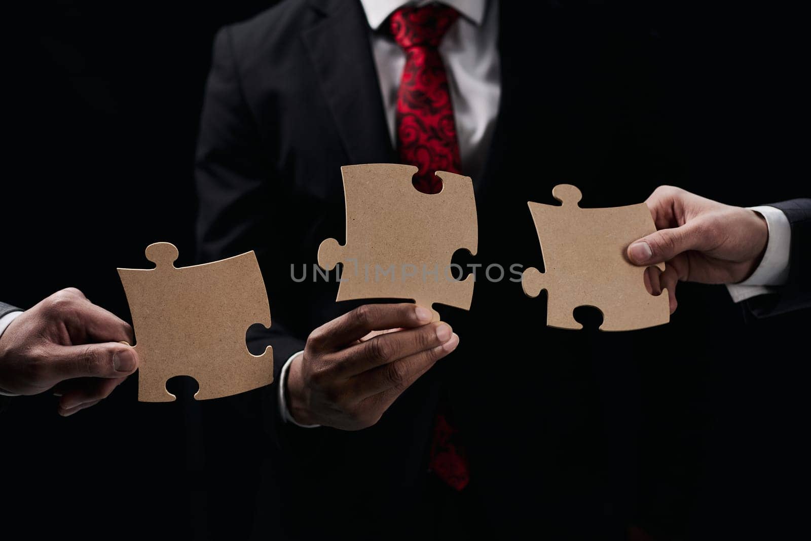 See the big picture. Close-up of an unknown business man holding three pieces of a puzzle together.