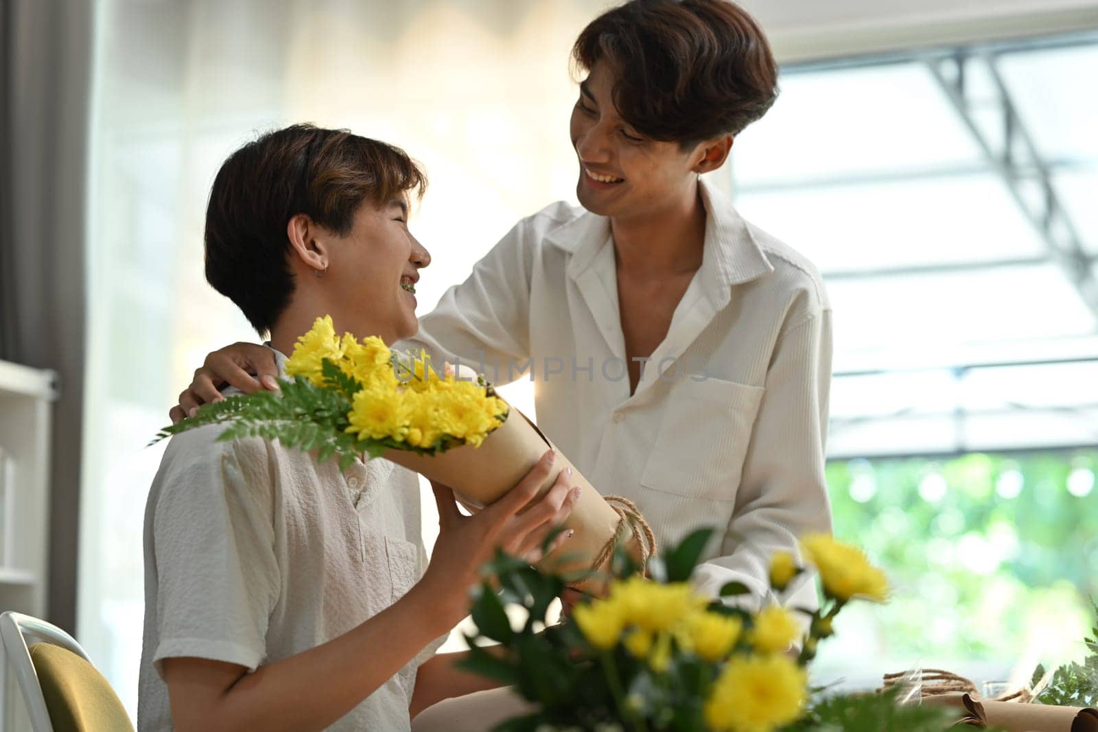 Shot of romantic asian man giving a bunch of flowers to his boyfriend. LGBTQ people lifestyle and love emotion.