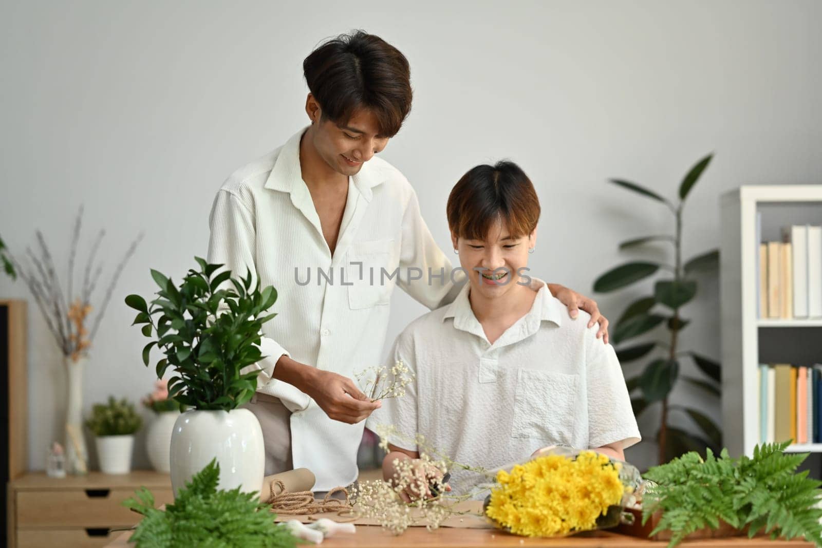 LGBT, love moments and lifestyle concept. Affectionate male gay couple spending time together, enjoying arranging flowers in cozy home.